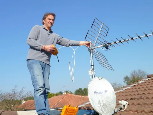 Technicien antenniste réglant une antenne TV